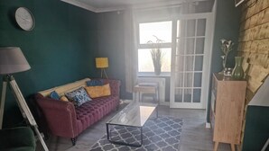 A living room with a red sofa, patterned cushions, a coffee table, and a patterned rug. - 2br-sleeps4-balcony-petsok-parking-ferryside (Kidwelly)