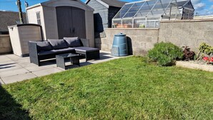 A patio with a sofa and table, a greenhouse, and a small shed. - 3br-sleeps6-petsok-off Road Parking-garden (Kidwelly)