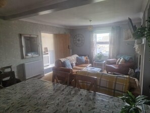 A living room with a sofa, armchairs, a dining table, and a large mirror.