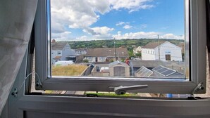 A window with a view of a residential area, including houses and a small building. - 3br-sleeps6-petsok-off Road Parking-garden (Kidwelly)
