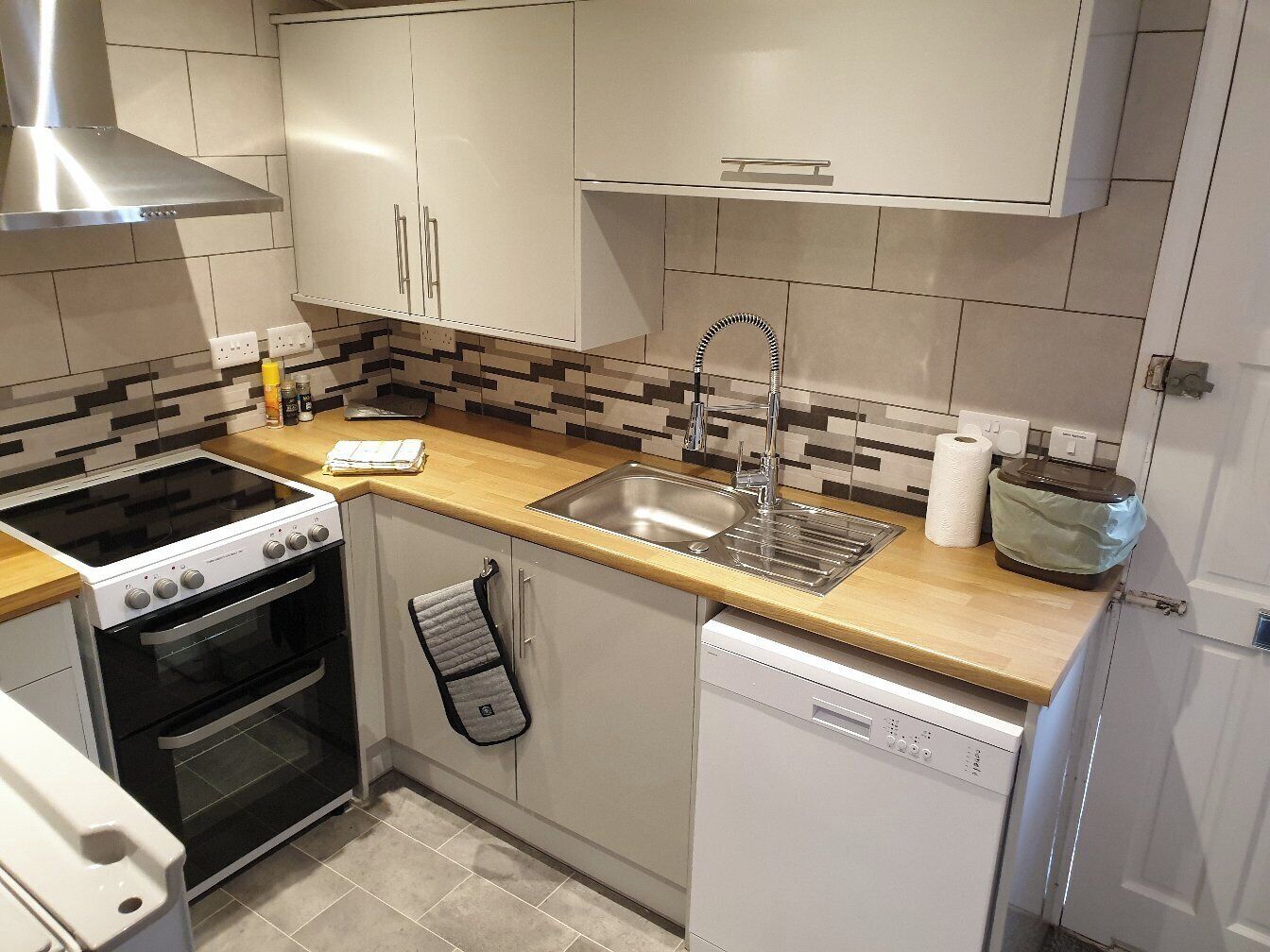 Een moderne keuken met een kookplaat, oven, spoelbak en vaatwasser.