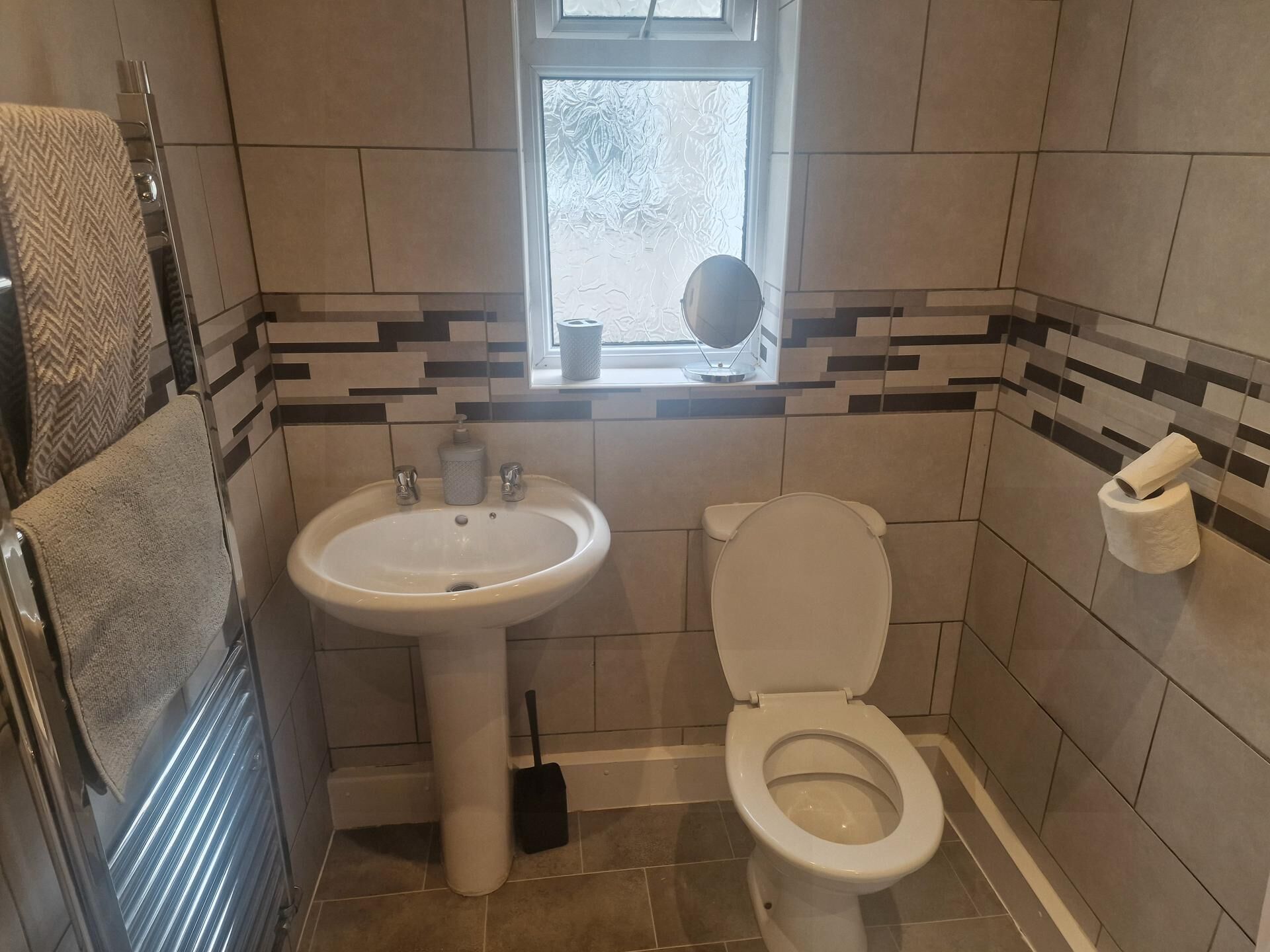 Un bagno con lavandino, WC e finestra.