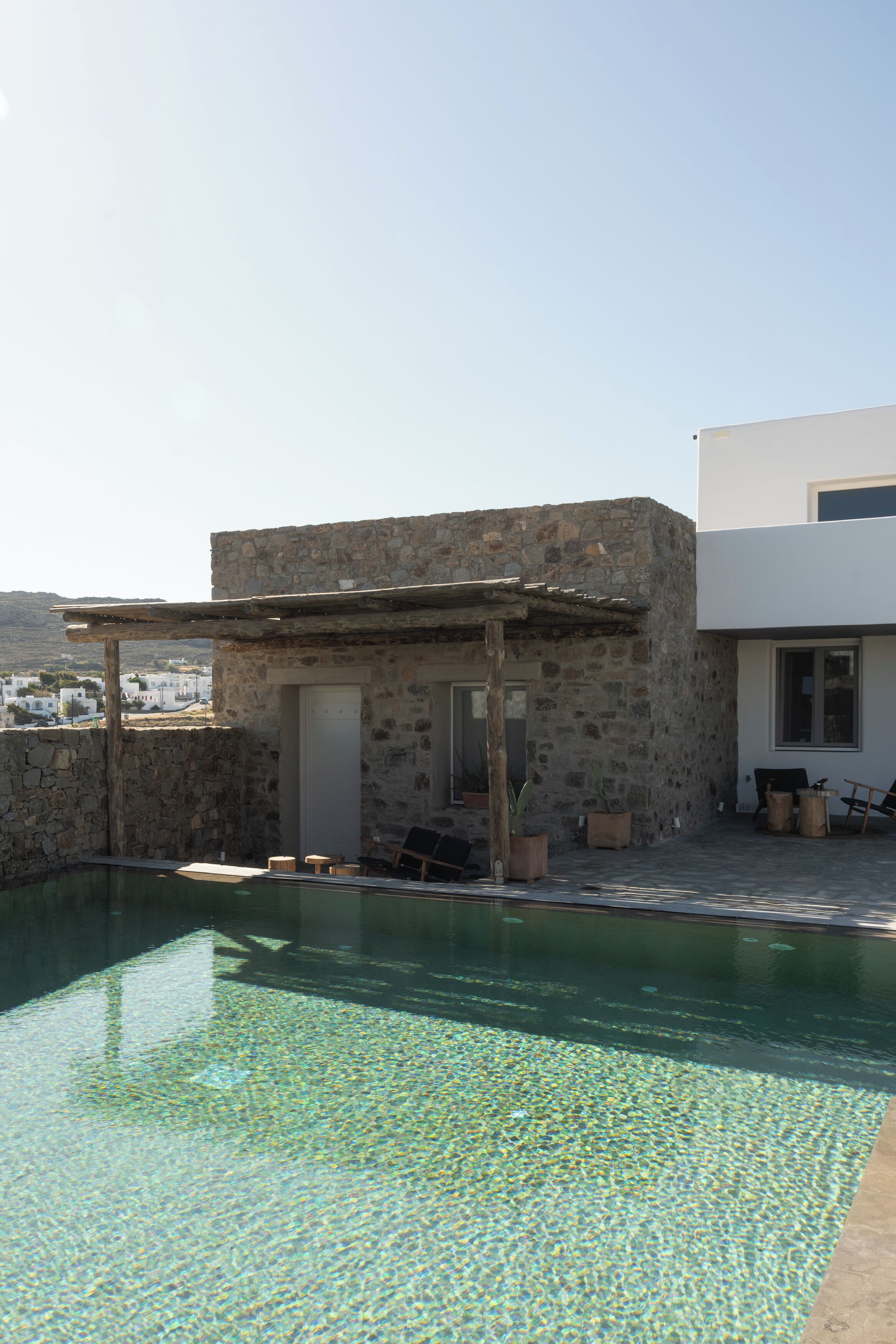 A stone building with a pool, a pergola, and a view of the landscape.