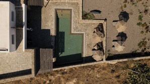 Vista aérea de um pátio com piscina, área de estar externa e muros de pedra.