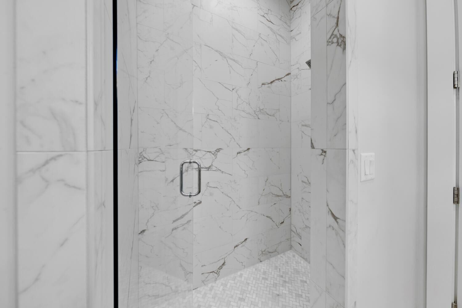 A bathroom with white marble walls and a tiled floor.