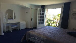 A bedroom with a bed, a desk, a chair, a wardrobe, and a balcony with a view of greenery. - Faïza  - Four Bedroom Villa, Sleeps 8 (Roquebrune-sur-Argens)