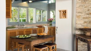 A kitchen with wooden cabinets, a stone wall, and a window overlooking greenery. - AMPLE PLACES Monadiko House
Traditional house in the center of Lefkara village (Pano Lefkara)