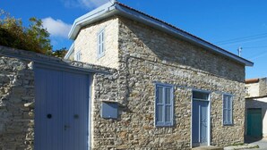 A stone building with a gabled roof, a large garage door, and shutters on the windows. - AMPLE PLACES Monadiko House
Traditional house in the center of Lefkara village (Pano Lefkara)
