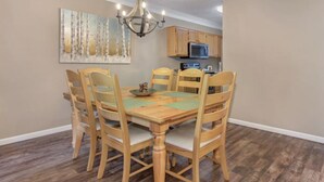 A dining area with a wooden table and chairs, a chandelier, and a painting on the wall. - Walk-in Level | 2 BR | Balcony | Sleeps 6 | Free Tickets (Pigeon Forge)