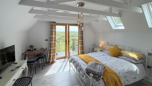 Una camera da letto con un letto, una scrivania, una sedia e un balcone con vista.