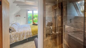 Una camera da letto moderna con un letto, una doccia e vista sul verde.