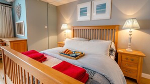 A neatly arranged bedroom with a bed, bedside tables, and a wooden headboard. - 1 bedroom accommodation in Newquay (Newquay)