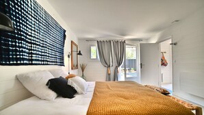 A bedroom with a bed, white walls, a window with curtains, and a door leading to another room. - Casa Marcel, 4 Chambres, 4 Sdb, Décoration Bohème, au Calme Dans la Pinède (La Tremblade)