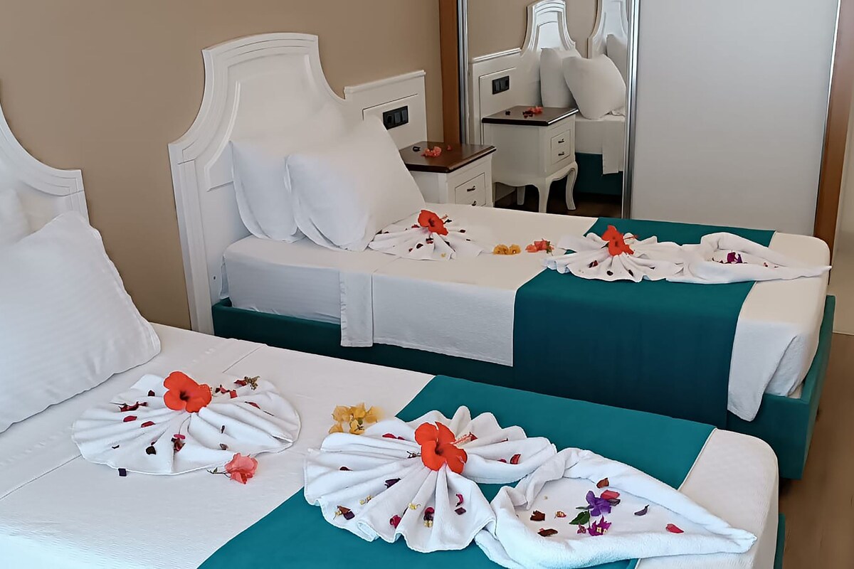 Et hotelværelse med to senge, hver med hvide sengetøj og blomsterudsmykning.