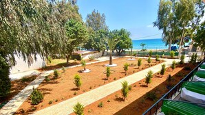 A landscaped garden with a pathway, small trees, and a view of the sea.