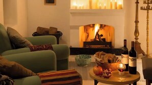 A cozy living room with a fireplace, a sofa, a coffee table with wine and snacks, and a decorative candelabra. - AMPLE PLACES Polytimo House
Traditional house in the center of Lefkara village (Pano Lefkara)