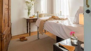 A bedroom with a bed, bedside table, dresser, mirror, and a small rug. - AMPLE PLACES Polytimo House
Traditional house in the center of Lefkara village (Pano Lefkara)