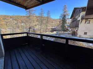 A wooden deck with a view of a mountainous landscape and buildings.