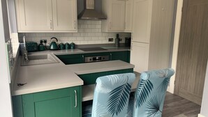 A kitchen with green cabinets, a white countertop, and a sink. There are green kettles and a toaster on the counter. - Impeccable 1-bed House in Aberdare (Aberdare)