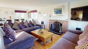 A living room with a fireplace, sofas, a coffee table, and a television. - Discover coastal bliss at The Dunes, your perfect family haven by Beadnell Bay. (Beadnell)