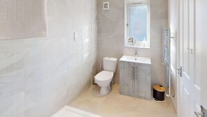 A modern bathroom with a toilet, sink, and shower. - Discover coastal bliss at The Dunes, your perfect family haven by Beadnell Bay. (Beadnell)