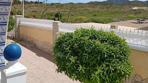 Vista a través de un arco blanco y azul con diseño, que da a un jardín ajardinado y vistas de colinas distantes.