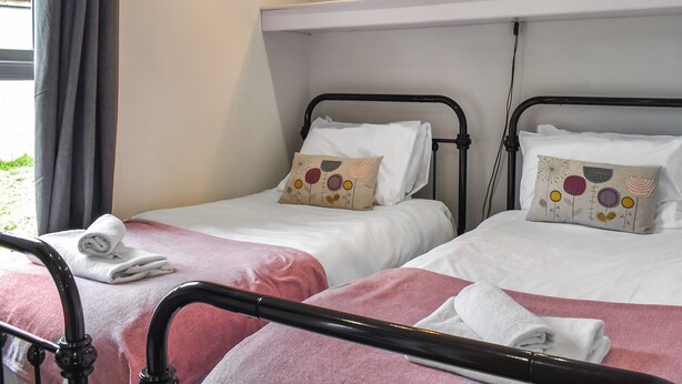Quarto de hotel com duas camas, cada uma com uma almofada e uma toalha enrolada.