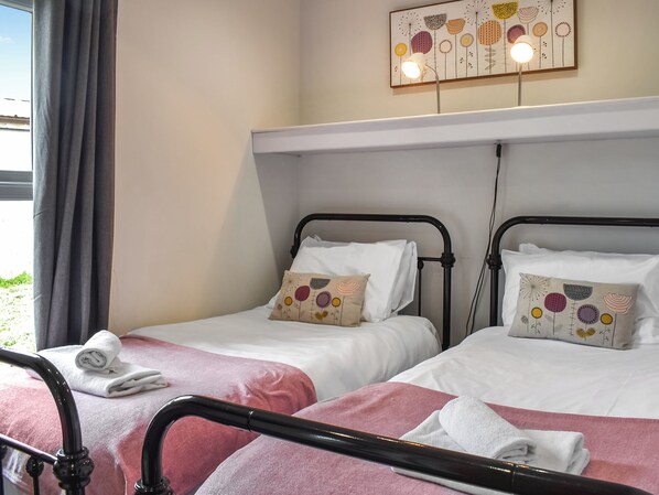 A hotel room with two beds, each with a pillow and a rolled towel.
