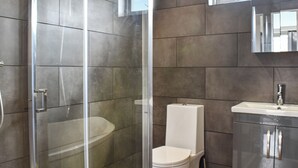 Une salle de bain moderne dotée d’une douche à parois de verre, de toilettes et d’un lavabo.