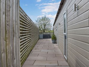 A narrow outdoor pathway with a wooden fence on one side and a building with siding on the other. - 4 bedroom accommodation in Kirkby Lonsdale (Kirkby Lonsdale)