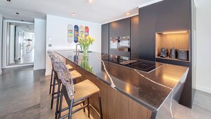 Une cuisine moderne dotée d’un îlot central, d’appareils électroménagers intégrés et d’un design minimaliste.