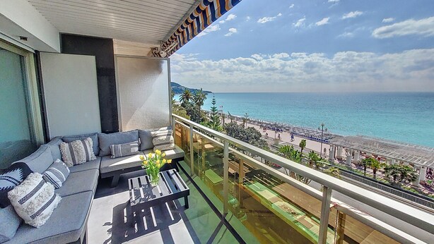 Un balcon avec un canapé, une table basse et une vue sur la plage et l’océan.