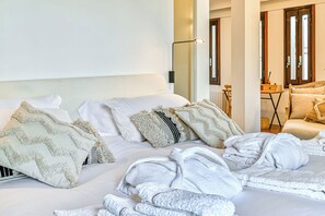 Quarto de hotel com cama, duas almofadas, mesa de cabeceira, luminária e cadeira.