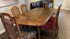 Un comedor con una mesa y sillas de madera, una estantería y un cuadro en la pared.