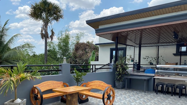 An outdoor patio area with a wooden table and benches, a grill station, and potted plants.