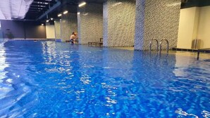 Una piscina interior con agua azul cristalina, paredes de azulejos y un banco a un lado.