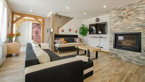 Una sala de estar moderna con un sofá, una mesa de centro, un televisor en la pared y una chimenea.
