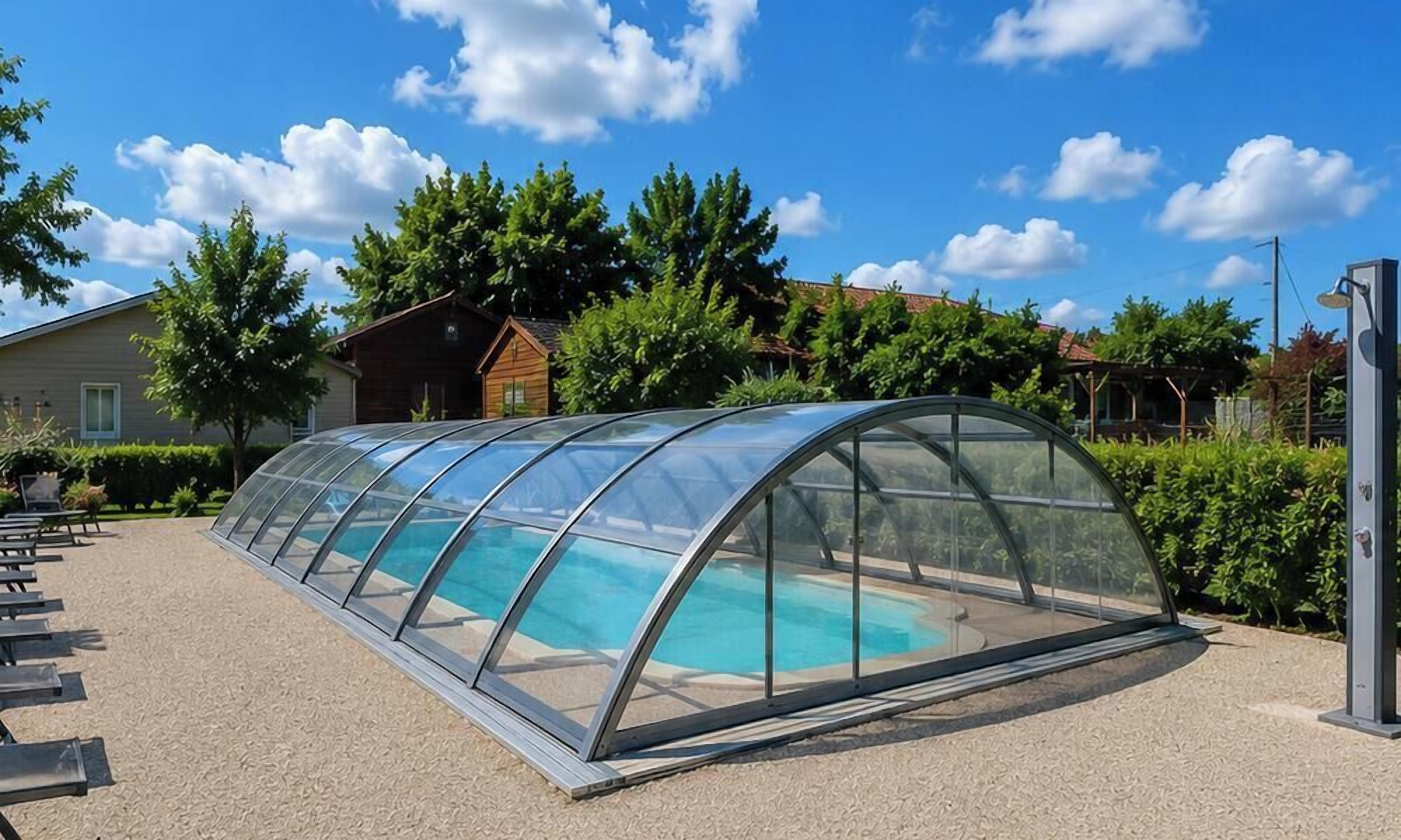 Une piscine couverte dotée d’un toit transparent, entourée d’une zone recouverte de gravier et de bancs.