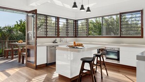 A modern kitchen with a large island, built-in appliances, and a view of the outdoors. - Allawah Cottage - Historic Beachside Retreat With Pippi Beach Views - Holiday Yamba (Yamba)