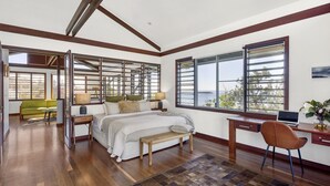 A bedroom with a large bed, a desk, a chair, and a view of the sea. - Allawah Cottage - Historic Beachside Retreat With Pippi Beach Views - Holiday Yamba (Yamba)