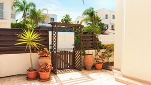 A patio with potted plants, a wooden gate, and a tiled floor. - Great 3 bedroom villa, with private pool, in the best location in Protaras (Protaras)