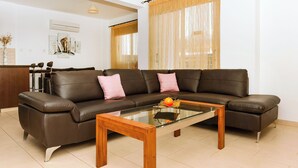 A living room with a brown leather sofa, a glass coffee table, and a wooden side table. - Great 3 bedroom villa, with private pool, in the best location in Protaras (Protaras)