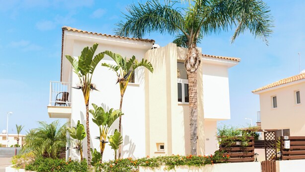 A two-story building with a balcony, surrounded by tropical plants and a palm tree. - Great 3 bedroom villa, with private pool, in the best location in Protaras (Protaras)