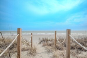 Eine hölzerne Strandabsperrung mit Seilen, Sandstrand und Ozean.