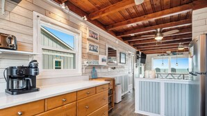 A kitchen with wooden cabinets, a coffee maker, and a view of the beach. - Dreamy Days: Coastal Cottage with Awe-inspiring Oceanfront Setting (Oak Island)