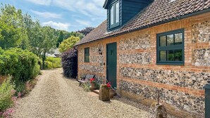 A stone house with a tiled roof, a gravel driveway, and a garden with flowers and shrubs. - 1 bedroom accommodation in Broad Chalke (Broad Chalke)
