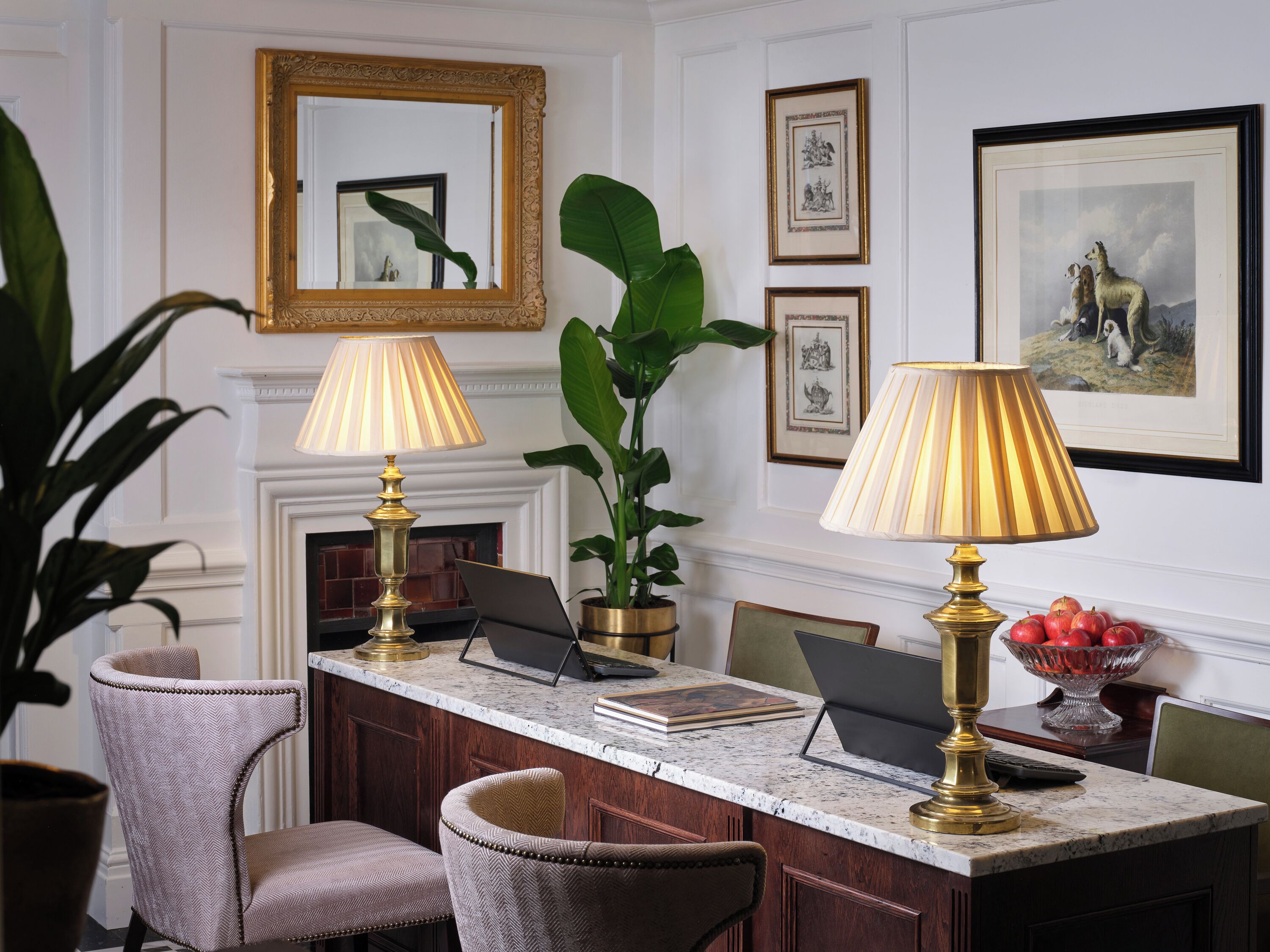 A formal dining area with a marble countertop, two lamps, a laptop, and framed artwork on the wall.
