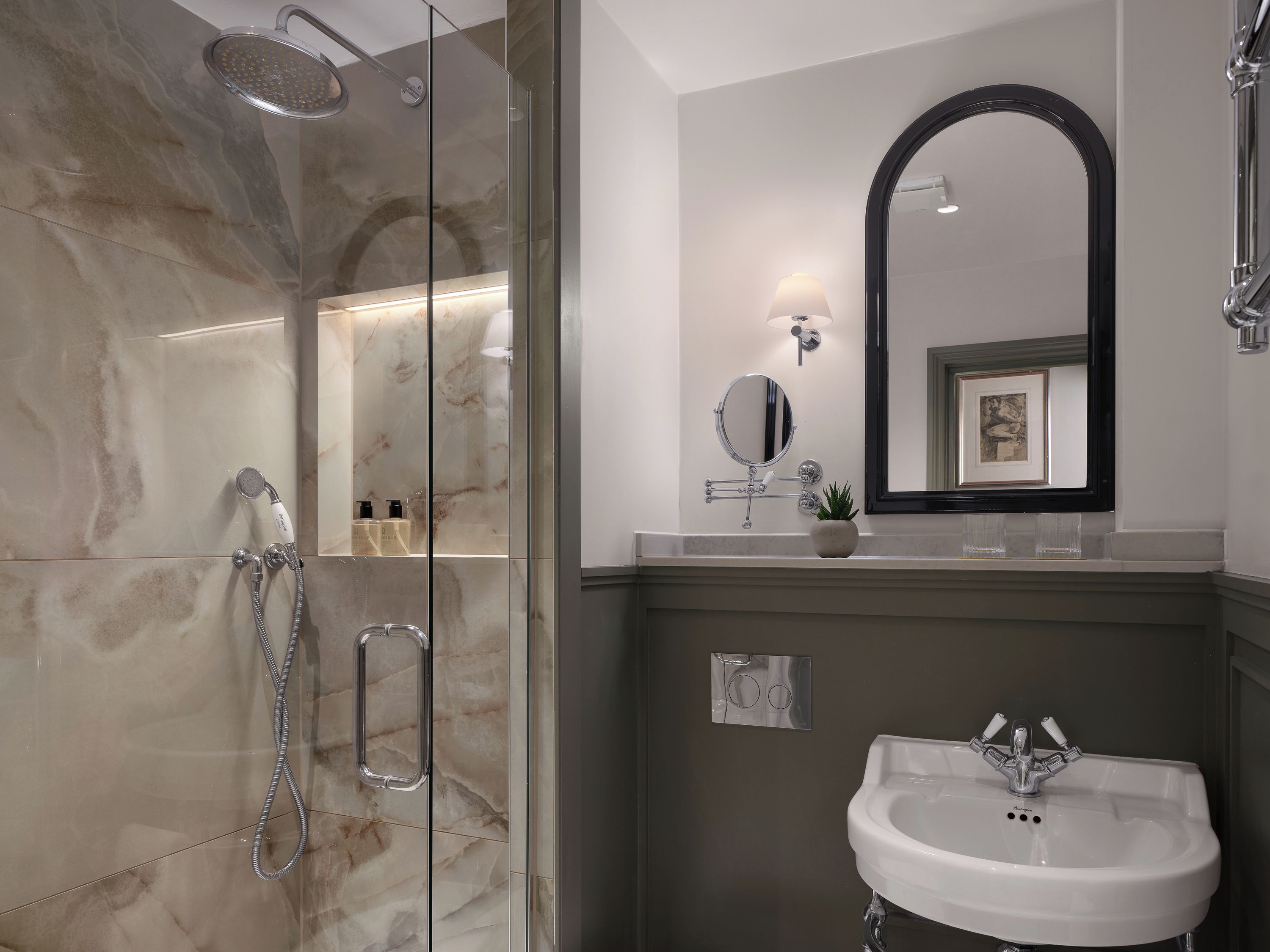 Une salle de bain moderne avec une douche à parois de verre, un lavabo blanc et un miroir encadré.