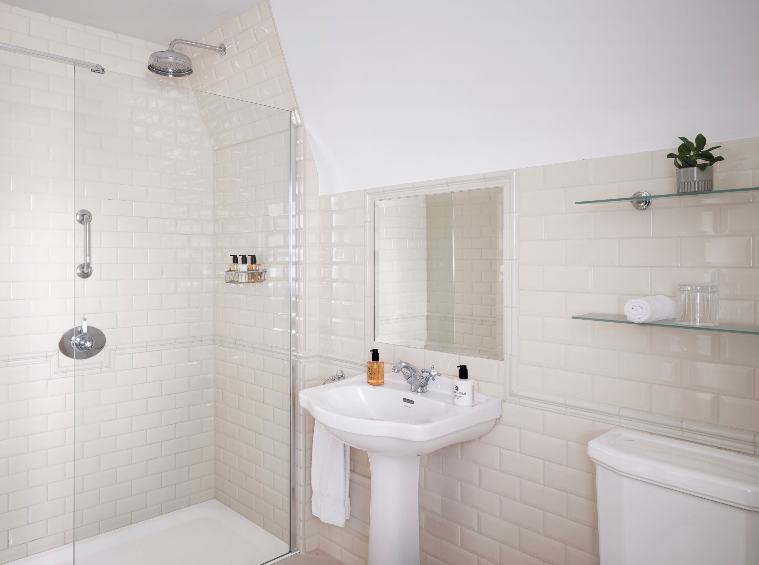 A modern bathroom with a glass-enclosed shower, a white sink, and a toilet.