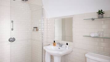 A modern bathroom with a glass-enclosed shower, a white sink, and a toilet.